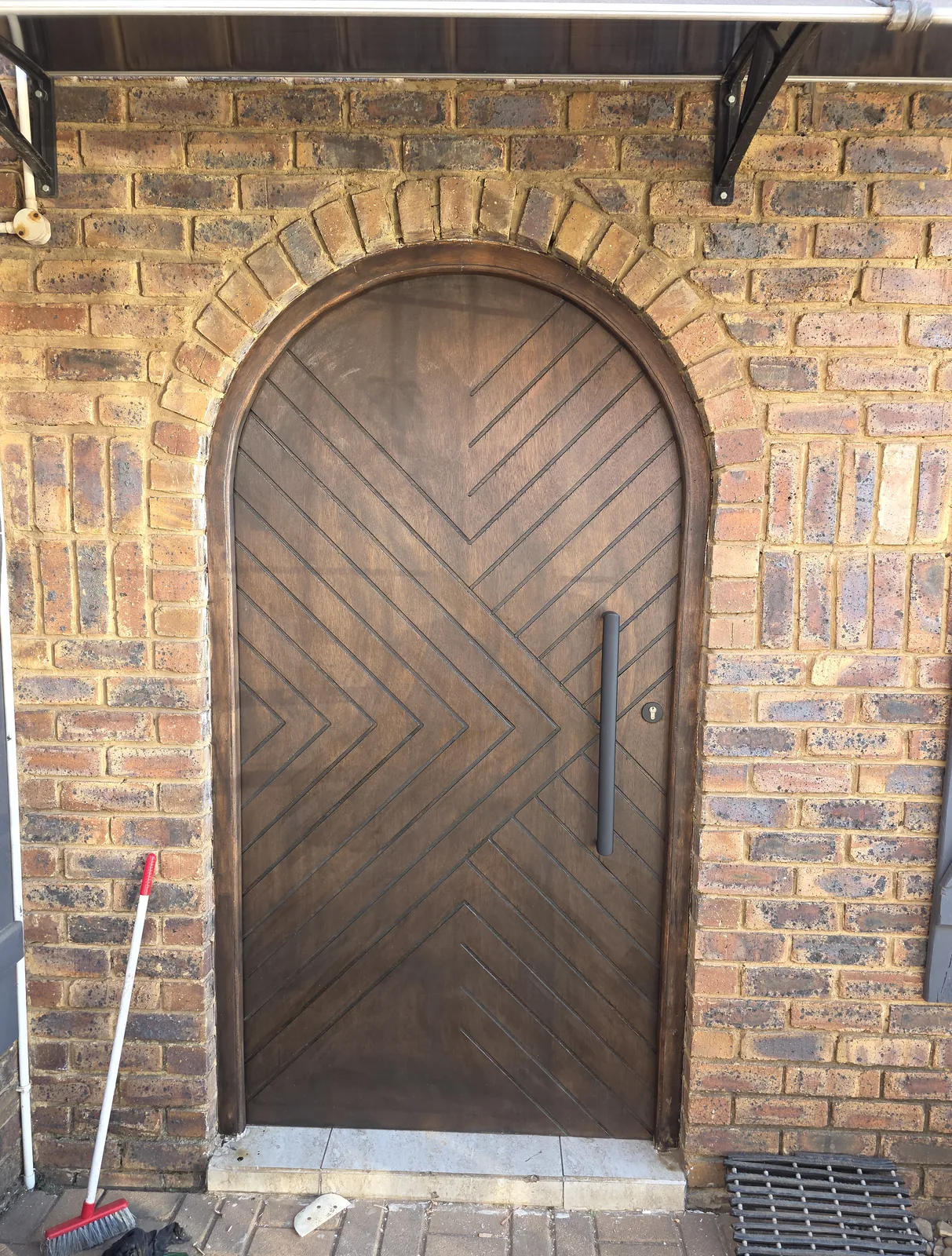 Bespoke stained hardwood arched entrance door with hand-cut chevron detailing, custom commission by Eminent Door & More, South Africa